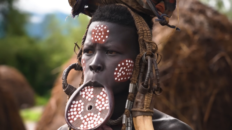 A woman from one of the tribes of Ethiopia wears a large painted lip plate and traditional accessories during a cultural gathering