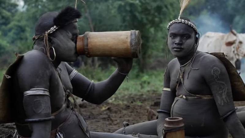 Two Bodi men in Ethiopia sit outdoors during the fattening ceremony