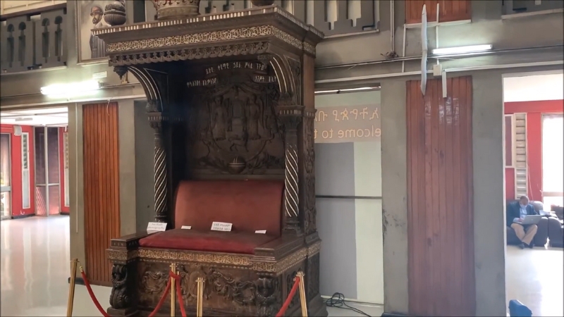 A royal wooden throne with detailed carvings is displayed on the ground floor of the National Museum of Ethiopia